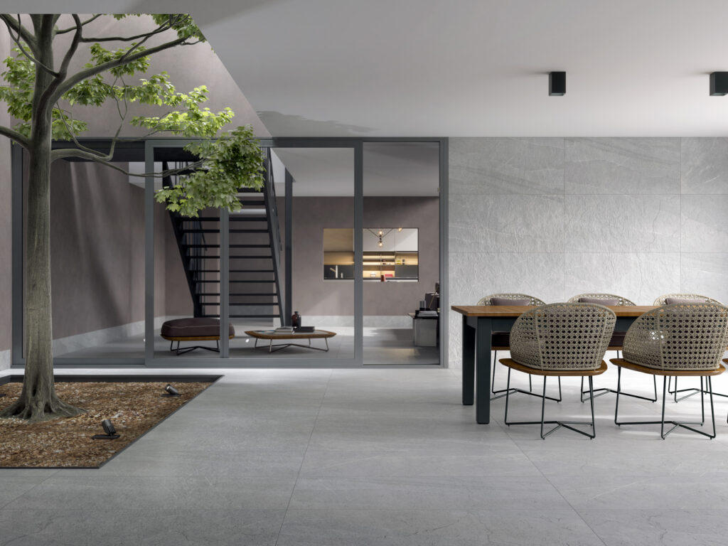 Tipus de terres per a reformes: gres porcelànic gris en pati modern amb mobiliari exterior.