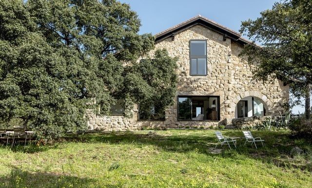 Fachada de casa de piedra rehabilitada en Ripollès, rodeada de naturaleza, ideal como segunda residencia.