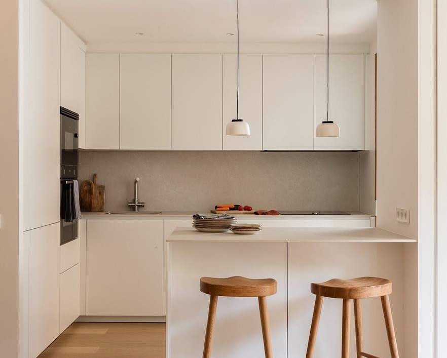 Cocina moderna con isla y muebles blancos en una vivienda de Vic